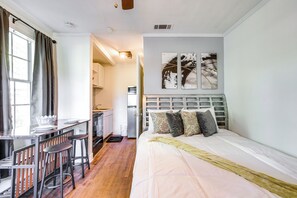 A bedroom with a bed, a desk with stools, a kitchen area, and a bathroom. - Sleek Couples Studio in Clarksdale! (Clarksdale)