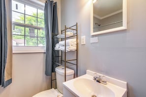 A bathroom with a white sink, a mirror, a towel rack, and a window with curtains. - Sleek Couples Studio in Clarksdale! (Clarksdale)