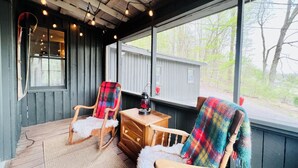 A cozy porch with two rocking chairs, a wooden table, and a lantern. - HOOTING HAUS - HOT TUB - FIRE PIT - CABIN RETREAT (Port Matilda)