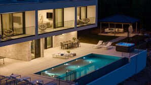 Een modern huis met twee verdiepingen, een zwembad, terras en een jacuzzi.
