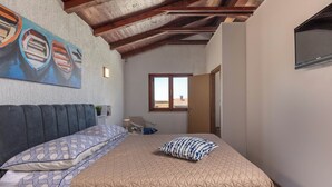 Un dormitorio con cama, un cuadro de barcos, techo de madera y ventana.