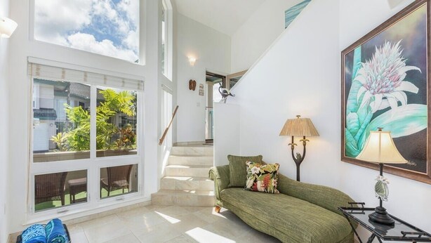 Una habitación amplia con un sofá verde, una lámpara y un cuadro en la pared.