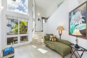 A spacious room with a green sofa, a lamp, and a painting on the wall. - Villas On The Prince 34 - Open & Spacious with A/C (Princeville)