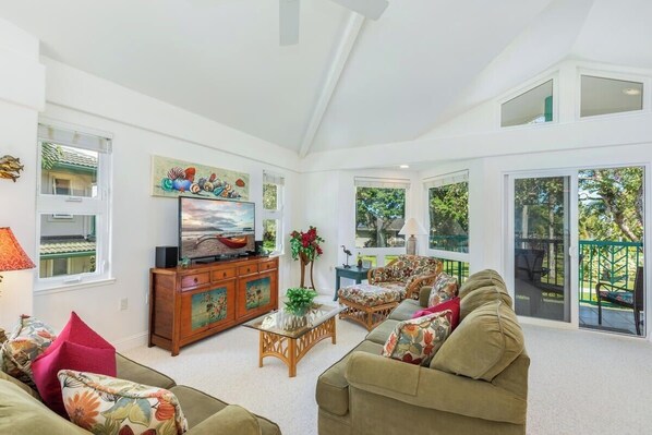 A spacious living room with a television, wooden cabinet, and comfortable seating.