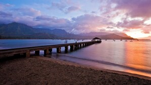 Un muelle se adentra en aguas tranquilas, con montañas al fondo.