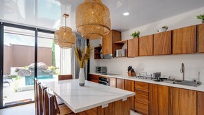Eine moderne Küche mit Holzausstattung, einer weißen Arbeitsplatte und hängenden Rattan-Leuchten.