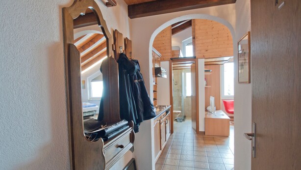 A narrow hallway with a wooden ceiling, a mirror, and a coat rack. - Studio Riffelsee (Zermatt)