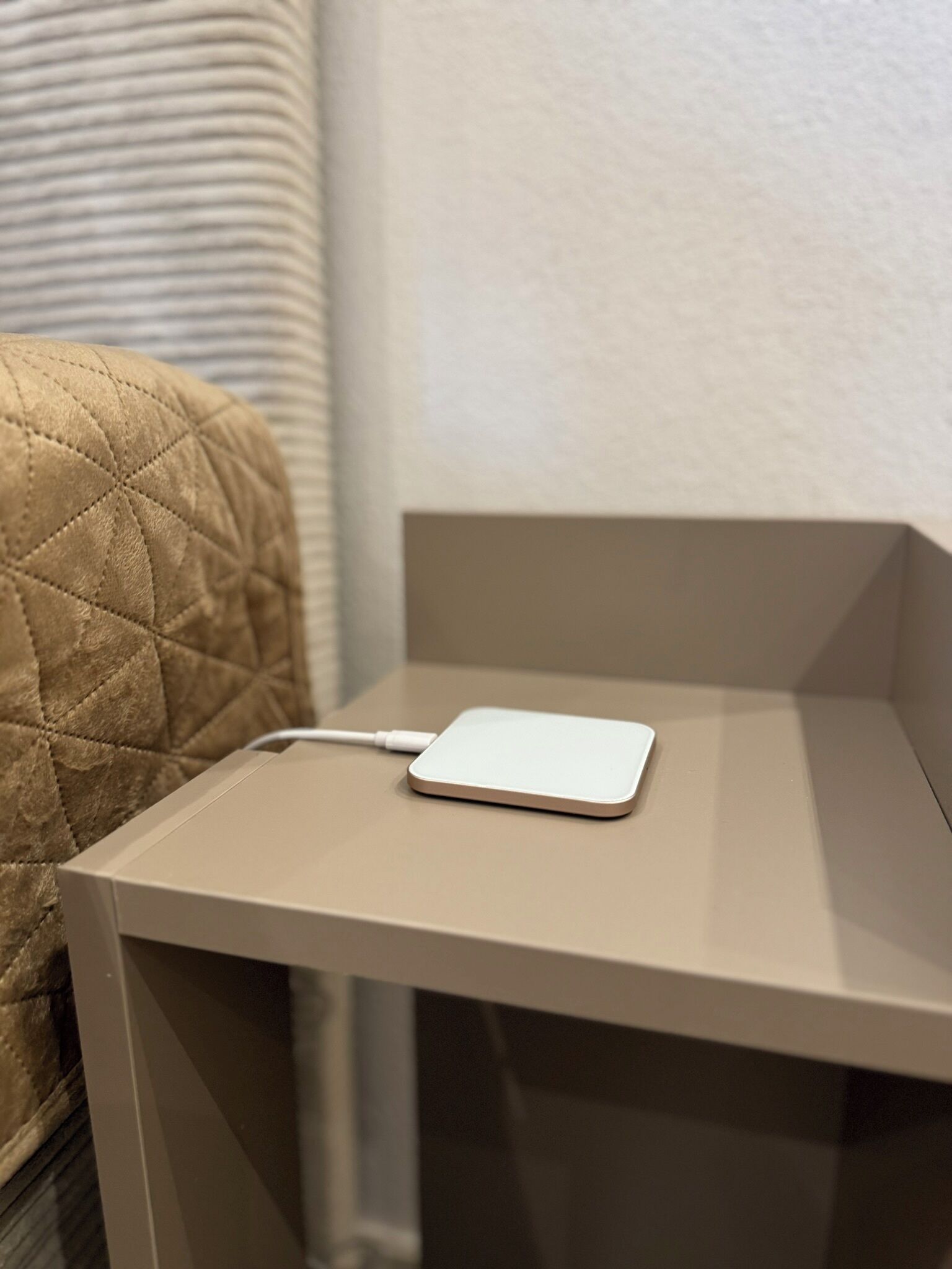 Un piccolo tavolo rettangolare con un dispositivo di ricarica bianco sopra.