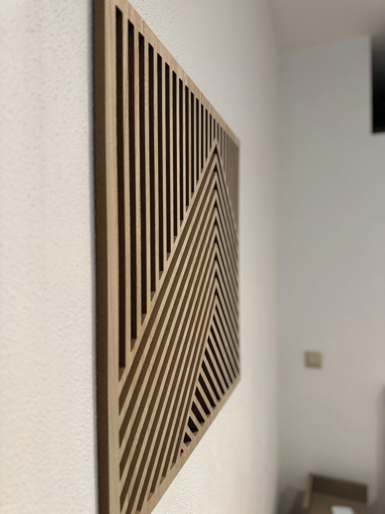 A wall-mounted geometric panel with a series of vertical and diagonal lines.