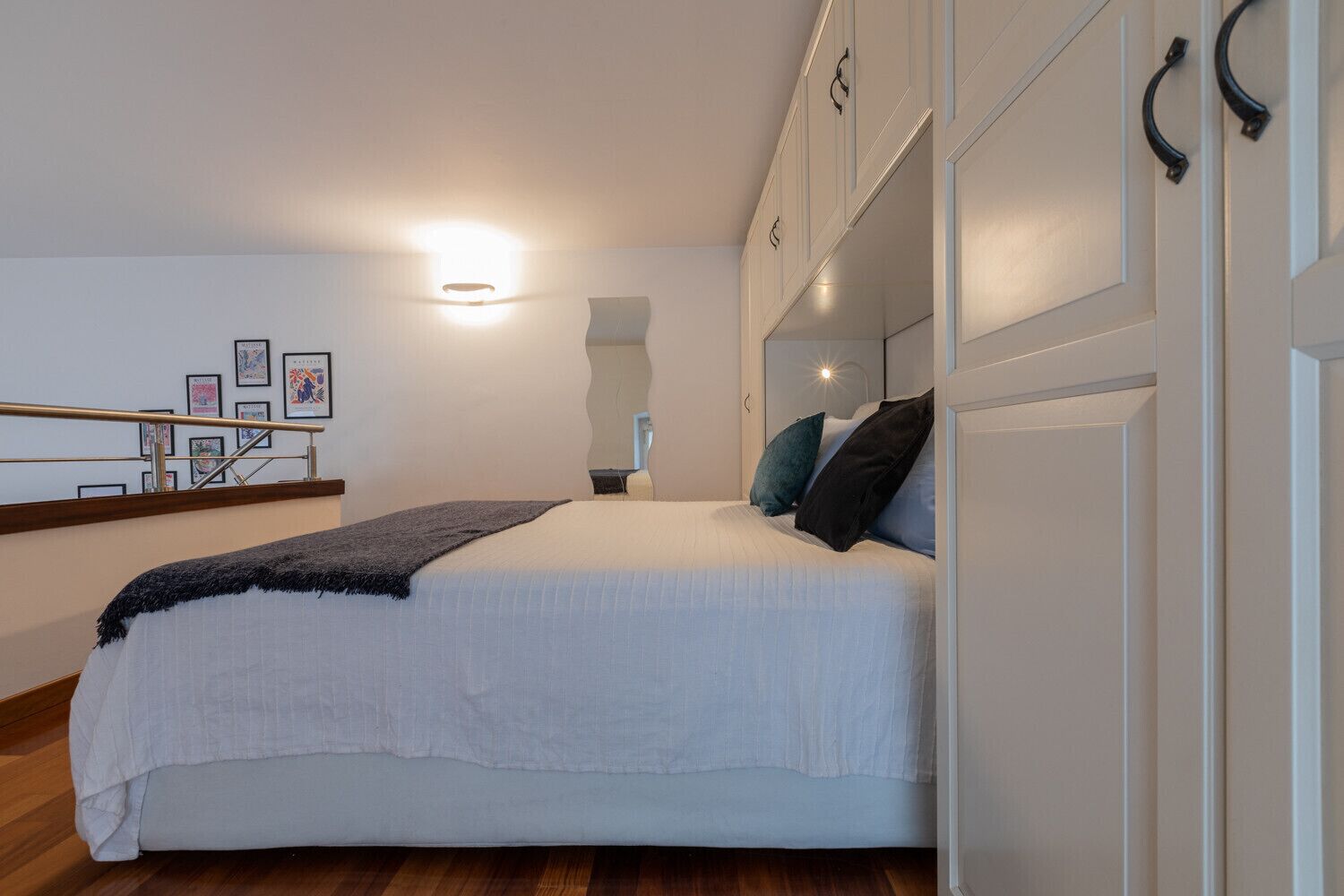 Un dormitorio con cama, mesita de noche, espejo y armario.