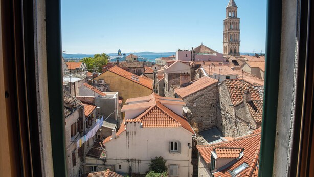 A view of a historic town with terracotta-roofed buildings, a prominent bell tower, and a clear blue sky. - Oblivion rooms (Split)