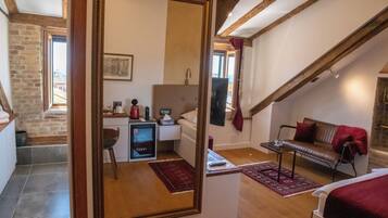 A room with a bed, a desk, a chair, a red rug, and a large mirror.