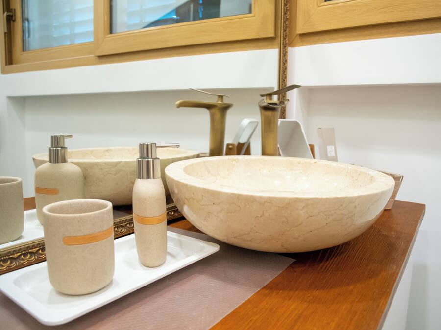 A bathroom with a large beige sink, two smaller sinks, and a mirror above.