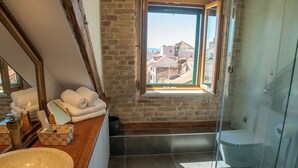 A bathroom with a large sink, a mirror, a window with a view of buildings, and a glass shower enclosure. - Oblivion rooms (Split)