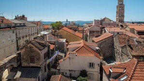 A historic town with closely packed buildings, a prominent clock tower, and a clear view of the sea. - Oblivion rooms (Split)