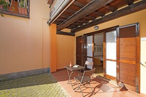 A patio with a table and chairs, a wooden ceiling, and a sliding door.