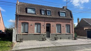 A two-story brick house with a tiled roof, multiple windows, and a small front porch. - Maison Familiale Avec Jardin (Avelin)