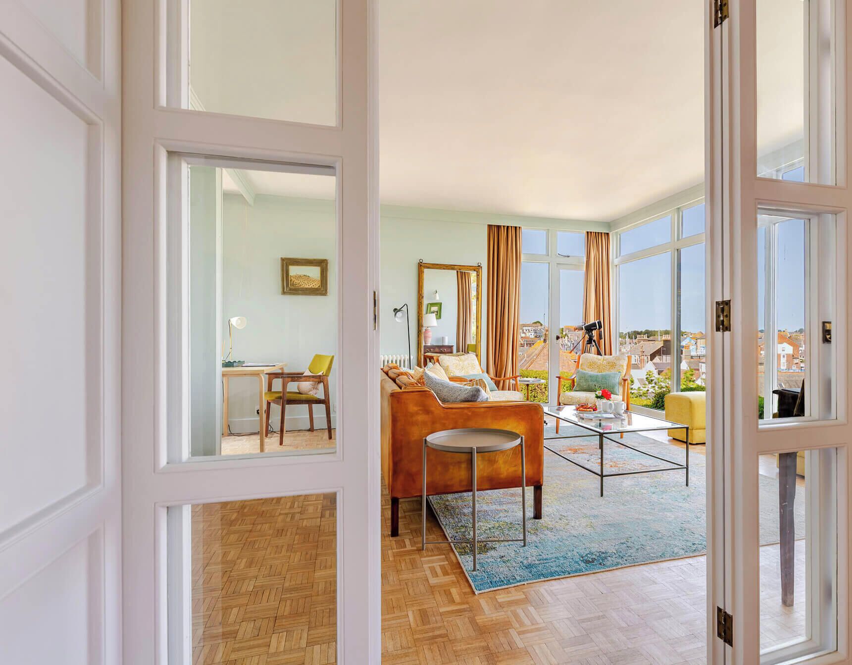Un espacio habitable abierto con sofá, sillas, una mesa de centro y vistas a la ciudad.
