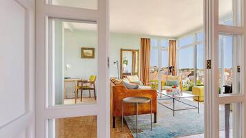 An open-plan living area with a sofa, chairs, a coffee table, and a view of the city.