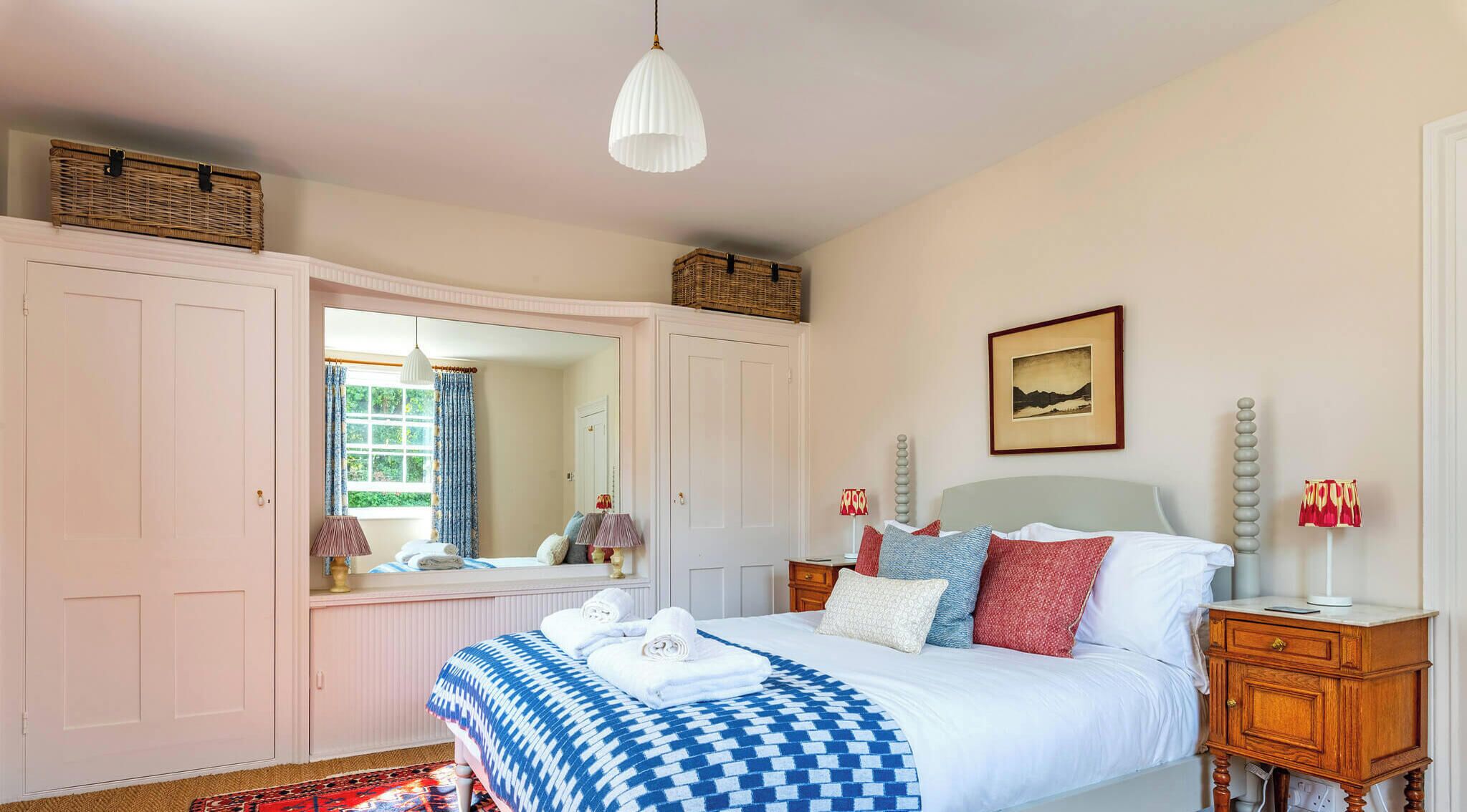 A bedroom with a bed, bedside tables, a mirror, and a picture on the wall.
