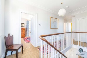 A staircase with a wooden handrail and white balusters, carpeted floors, and a framed map on the wall. - Nothe House - Exclusive home, Weymouth Harbour (Weymouth)