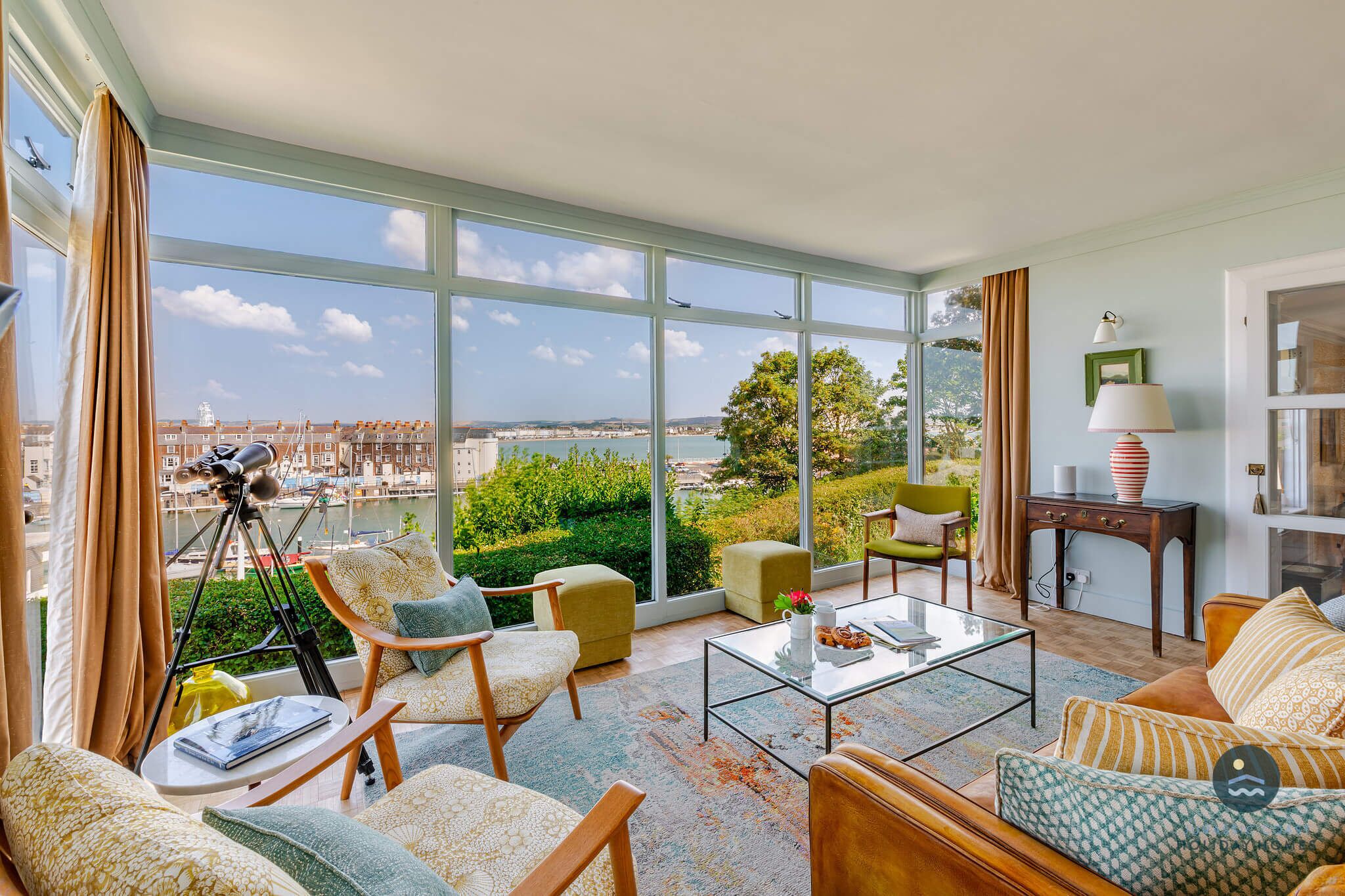 A spacious living room with large windows, a telescope, and a view of the city.