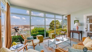 Un vaste salon doté de grandes fenêtres, d’un télescope et offrant une vue sur la ville.