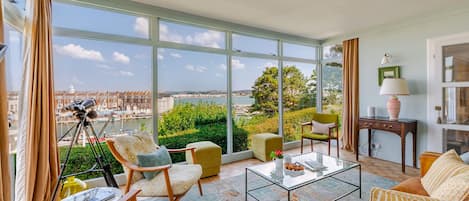 A spacious living room with large windows, a telescope, and a view of the city.