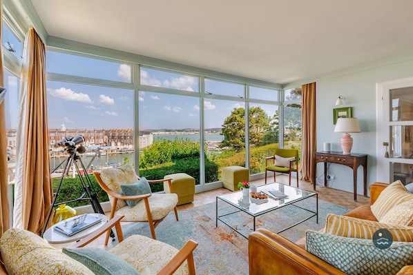 A spacious living room with large windows, a telescope, and a view of the city.