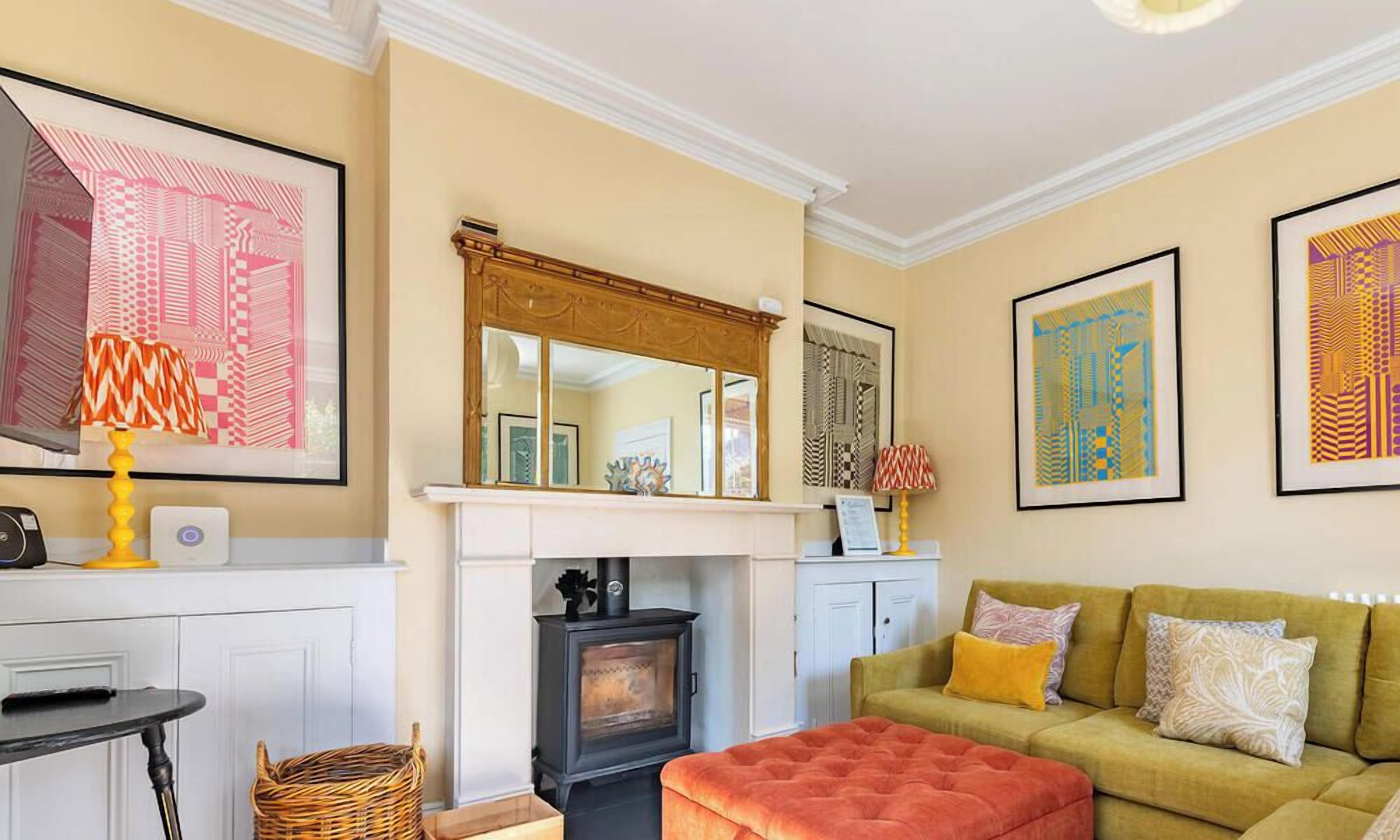 A living room with a fireplace, a sofa, a table, and framed artwork on the walls.
