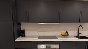 Une cuisine moderne avec des meubles de couleur sombre, un four en acier inoxydable et un évier.