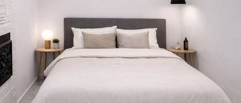 A modern bedroom with a bed, bedside tables, a wall-mounted light, and a ceiling light.