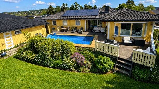 Une maison jaune avec une piscine, une terrasse et un espace salon extérieur.