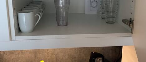 A kitchen with a stainless steel sink, a kettle, and a bottle of apple-flavored hand soap.