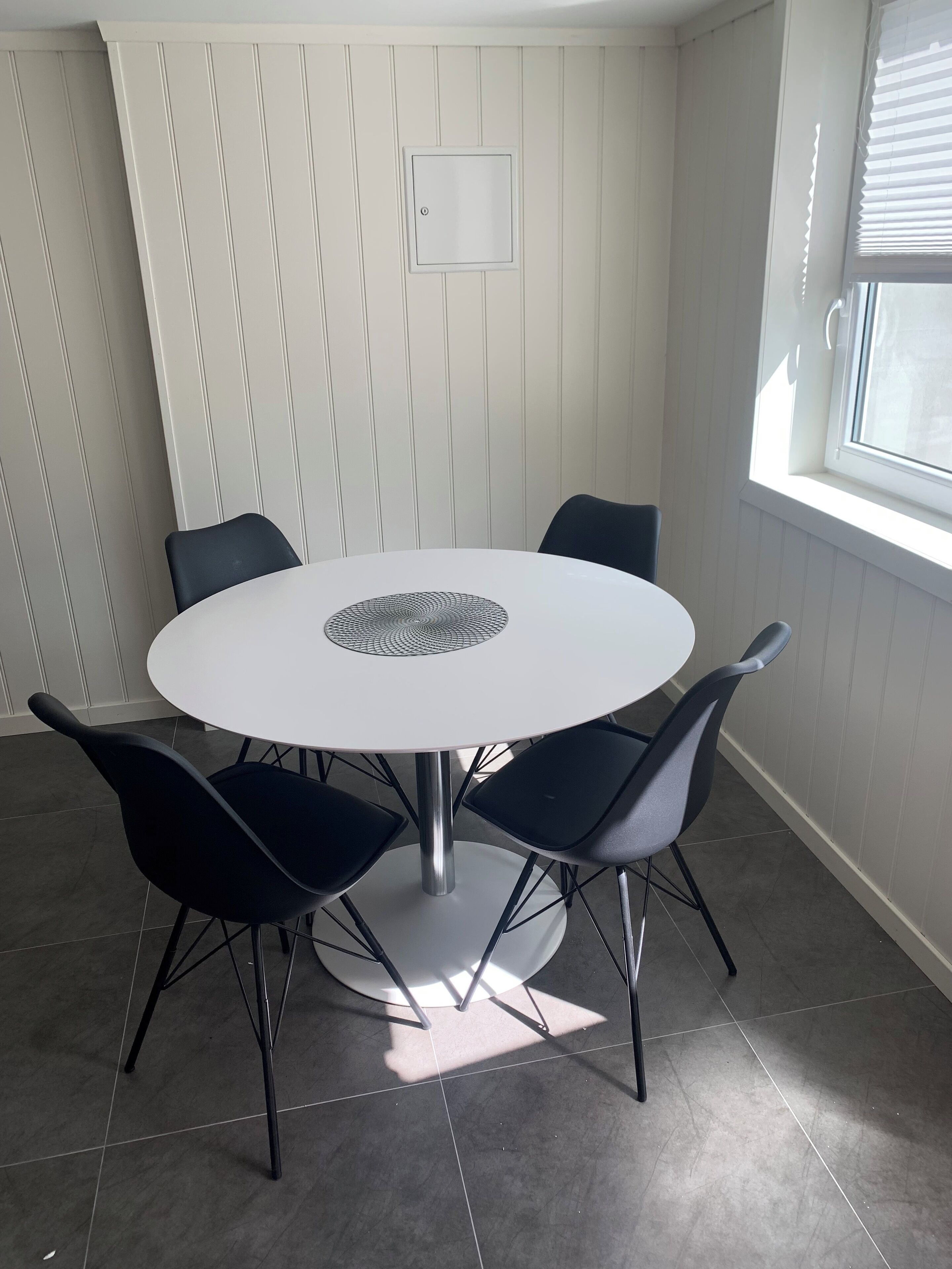 Una mesa redonda para comer con un adorno central, rodeada por cuatro sillas negras.