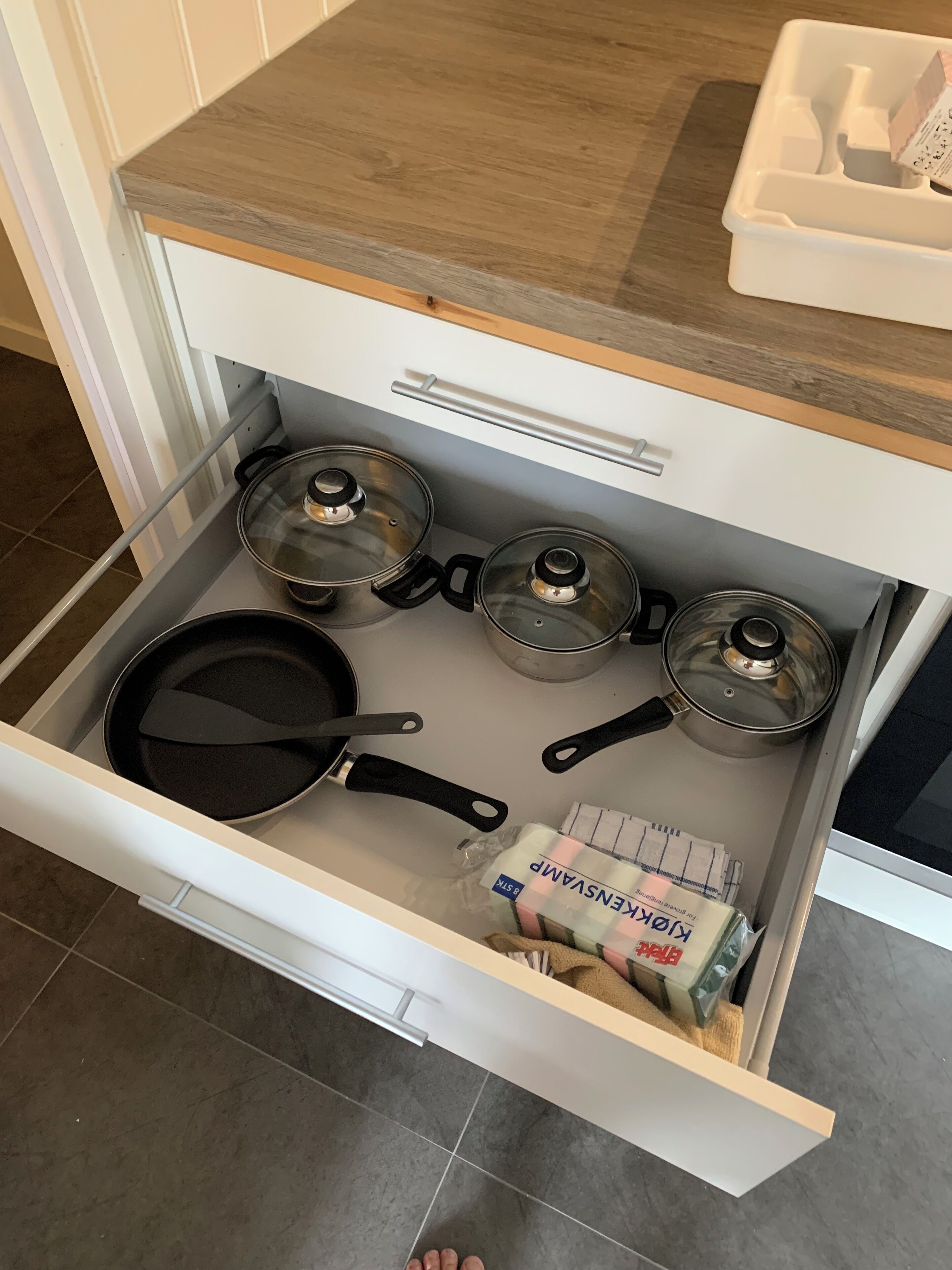A kitchen drawer with pots, pans, and a bag of flour.