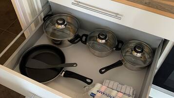 A kitchen drawer with pots, pans, and a bag of flour.
