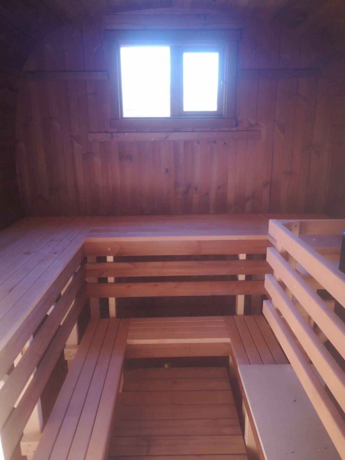 Een houten blokhut met een klein raam, een houten bank en een houten tafel.