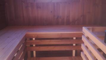 Een houten blokhut met een klein raam, een houten bank en een houten tafel.