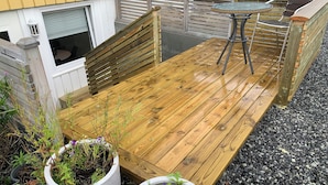 Une terrasse en bois avec une table et des chaises, entourée de plantes en pot.