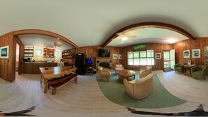 A spacious living area with a wooden dining table, wicker furniture, and a fireplace.