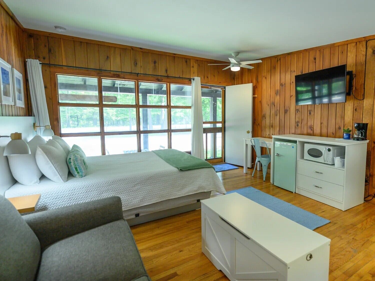 Une chambre comprenant un lit, un bureau, une télévision et un coin cuisine.