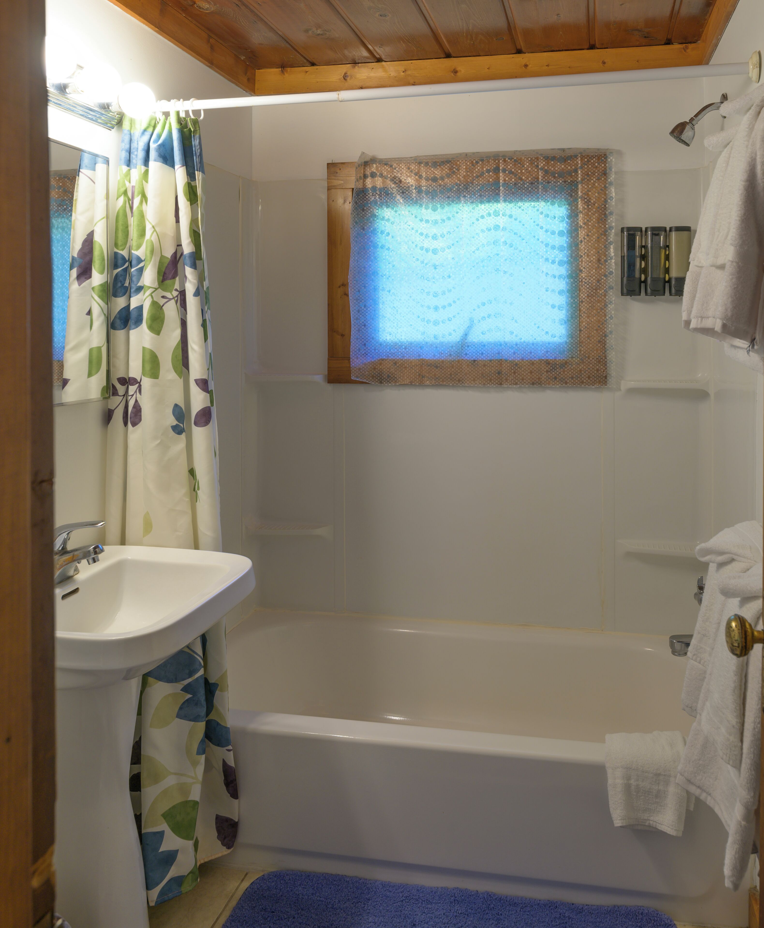Un baño con bañera, lavabo, ventana con vistas y zona de ducha.