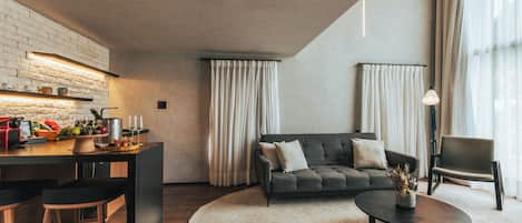 A modern living room with a sofa, a coffee table, and a kitchen area with a brick wall and bar stools.