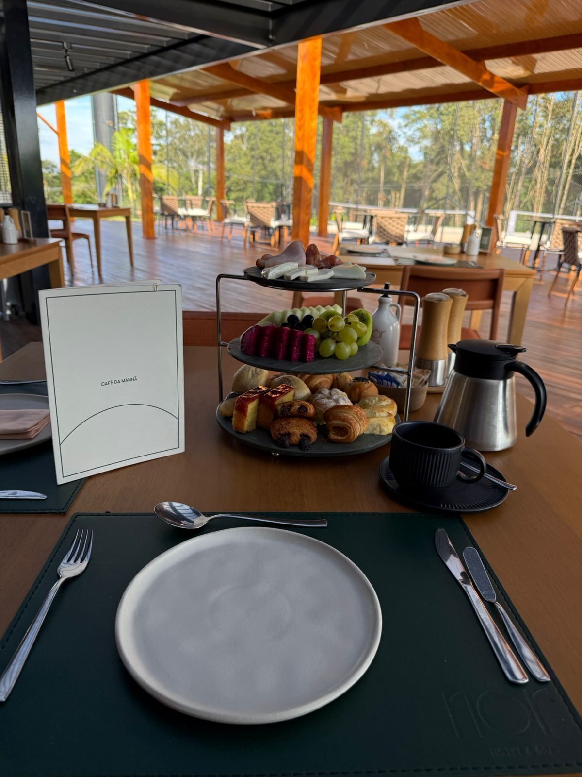 A breakfast setting with a plate, cutlery, a tray of pastries, and a menu.