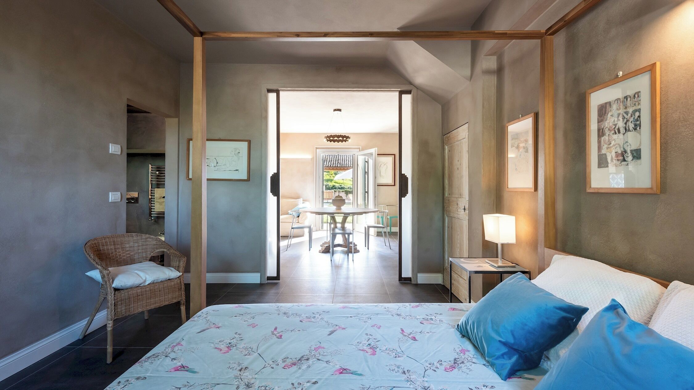 A hotel room with a bed, a chair, a table, and a lamp.