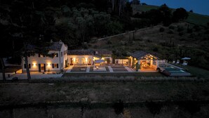 A large house with a swimming pool, outdoor seating, and a well-lit patio area.