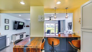 Une cuisine moderne avec une table à manger en bois, des tabourets de bar et un téléviseur encastré.