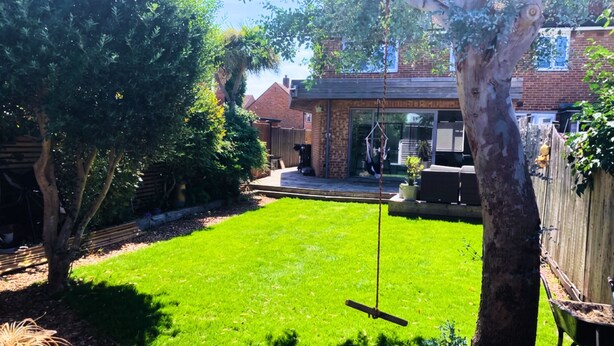 A backyard with a lawn, a swing set, and a wooden fence. - Chichester House I Secure Garden I Parking I Close to Goodwood (Chichester)