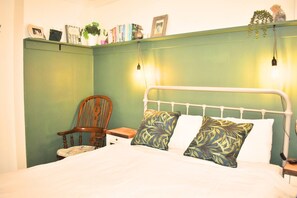 Une chambre à coucher comprenant un lit, une chaise, une table de chevet et des lampes fixées au mur.